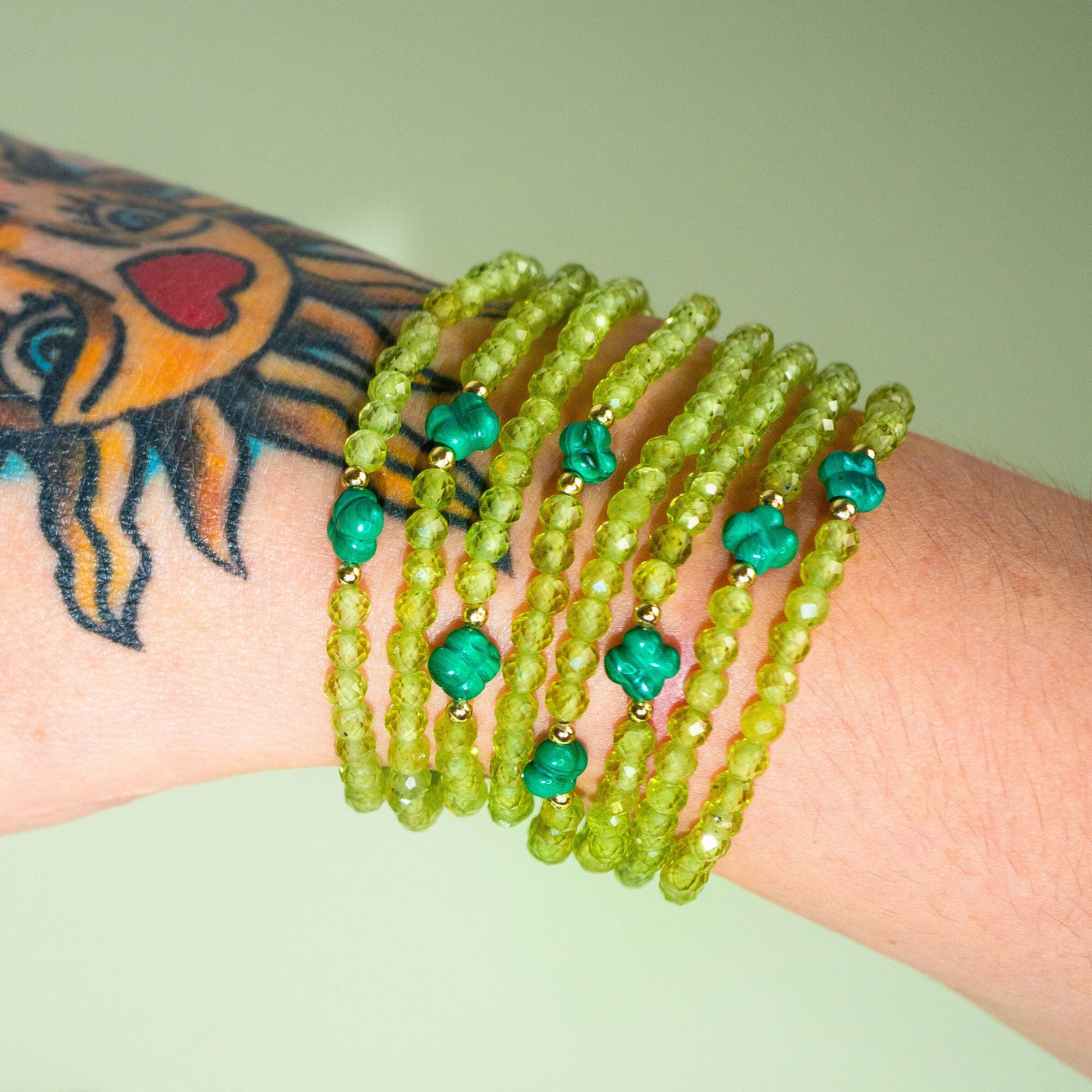 White woman with tarot sun hand tattoo wearing 8 Opportunity Magnet peridot and malachite crystal stretch elastic bracelets by Energy Muse