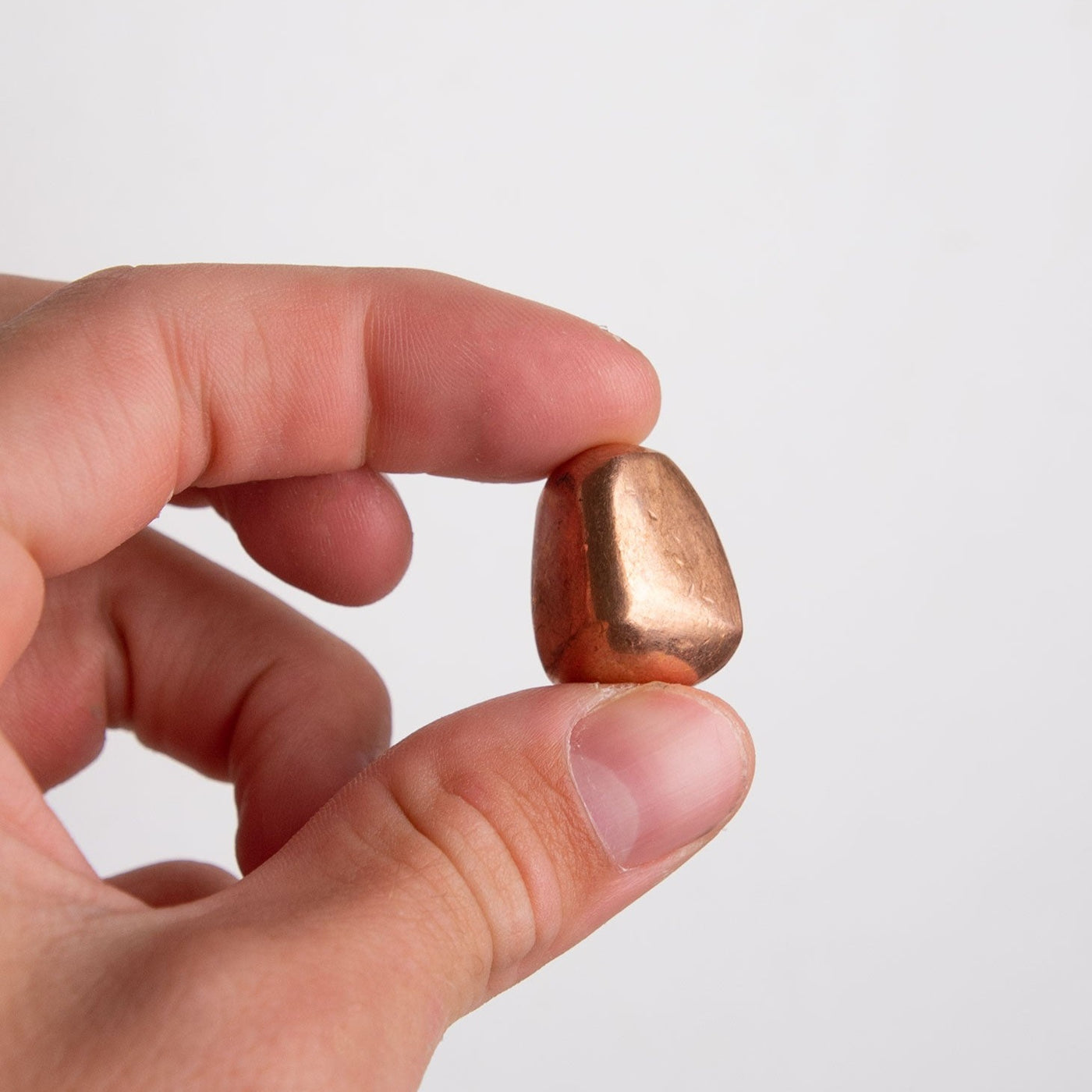 Man holding one copper tumbled stone in his hand to show size by Energy Muse 