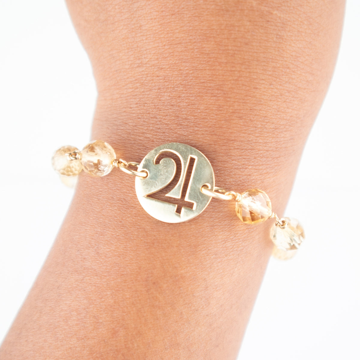 close up of woman wearing a sterling silver and citrine crystal bracelet with cutout pendant and Jupiter symbol on her wrist by Energy Muse