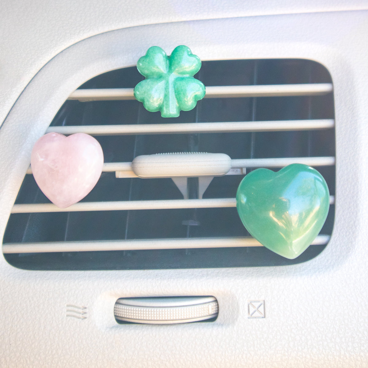 rose quartz heart car energy purifier, green aventurine car energy purifier and green aventurine clover car air energy purifier clipped onto the car's air vent by Energy Muse