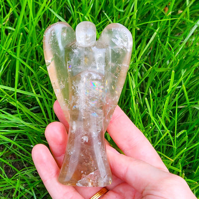 genuine Smoky Quartz angel carving shape by Energy Muse shown outside in natural light displaying the natural prismatic rainbows within