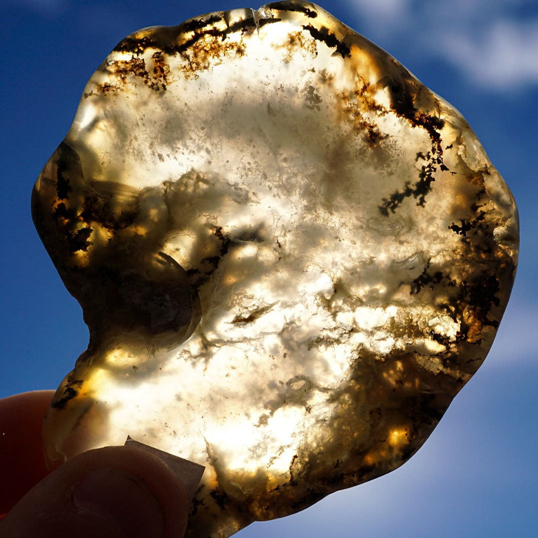 Closeup of Dendritic Opal Slab crystal held up to natural light by Energy Muse