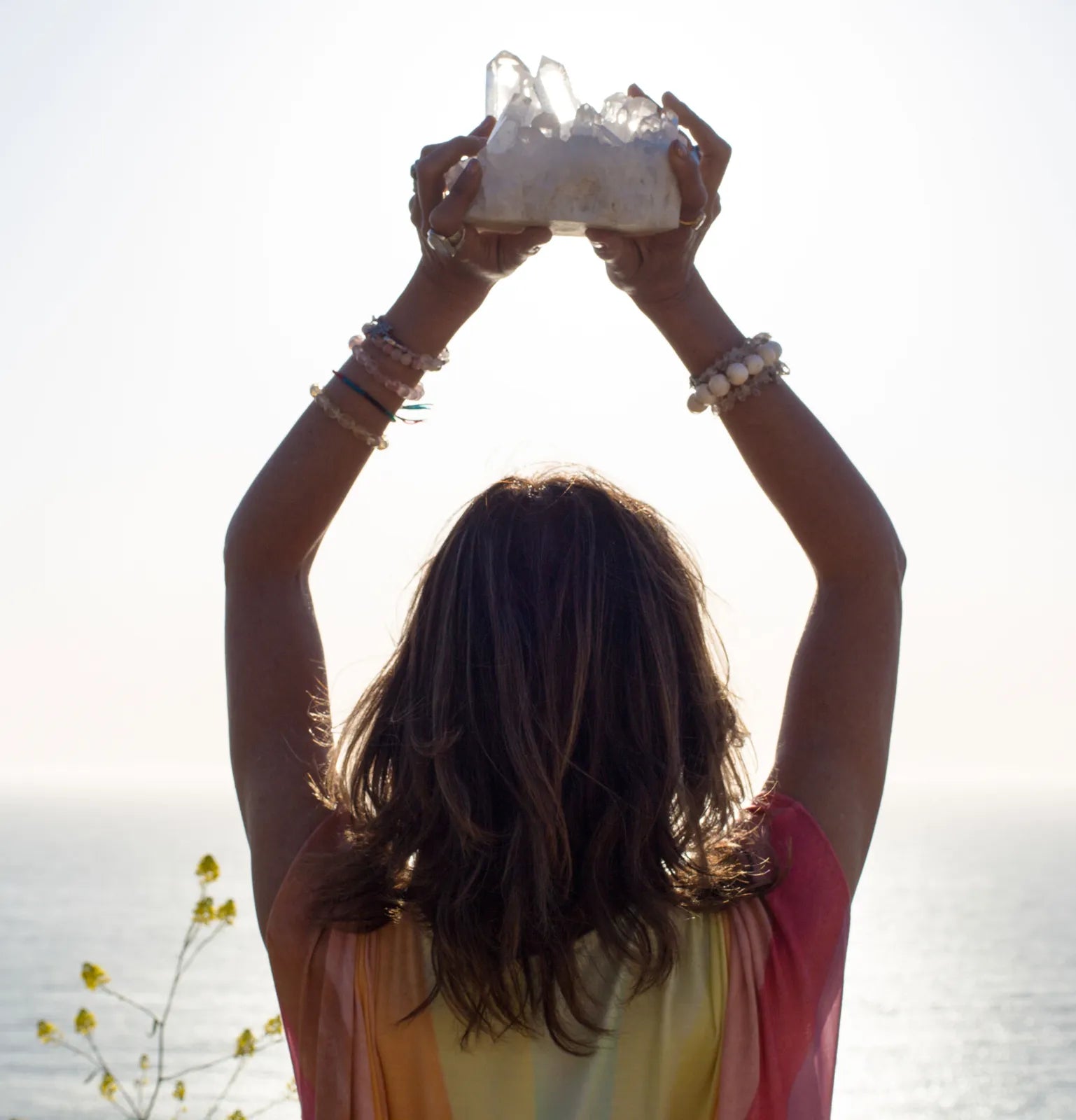 Heather holding a quartz cluster up to the light above the sea
