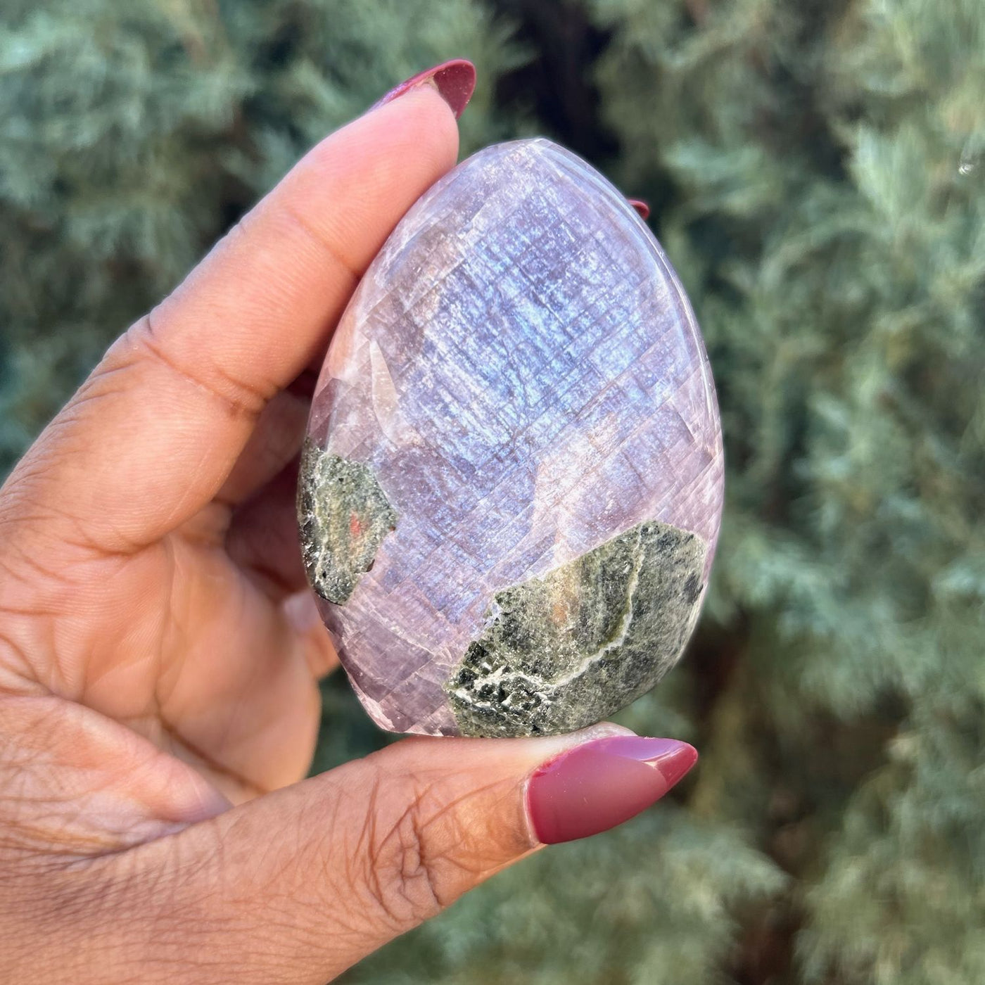 Woman holding Purple Anhydrite Freeform crystal outdoors in natural light, showing its partial shimmer - Energy Muse