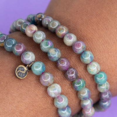 Close up view of Black woman's wrist wearing three stretch elastic Ruby in Kyanite genuine crystal bracelets by Energy Muse