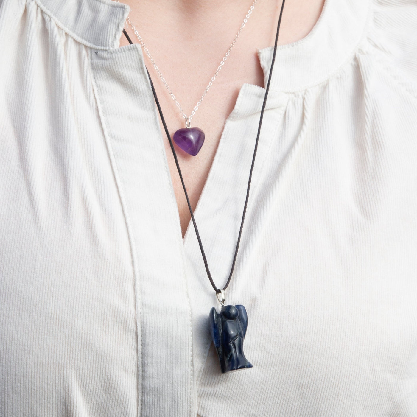 Woman wearing genuine Sodalite angel pendant necklace and genuine Amethyst heart pendant necklace by Energy Muse