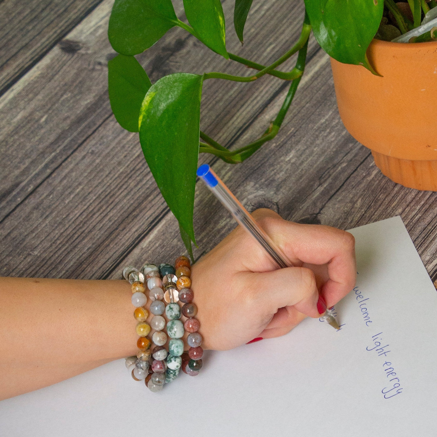 woman writing down intentions wearing Golden Sage Agate crystal bracelet by Energy Muse