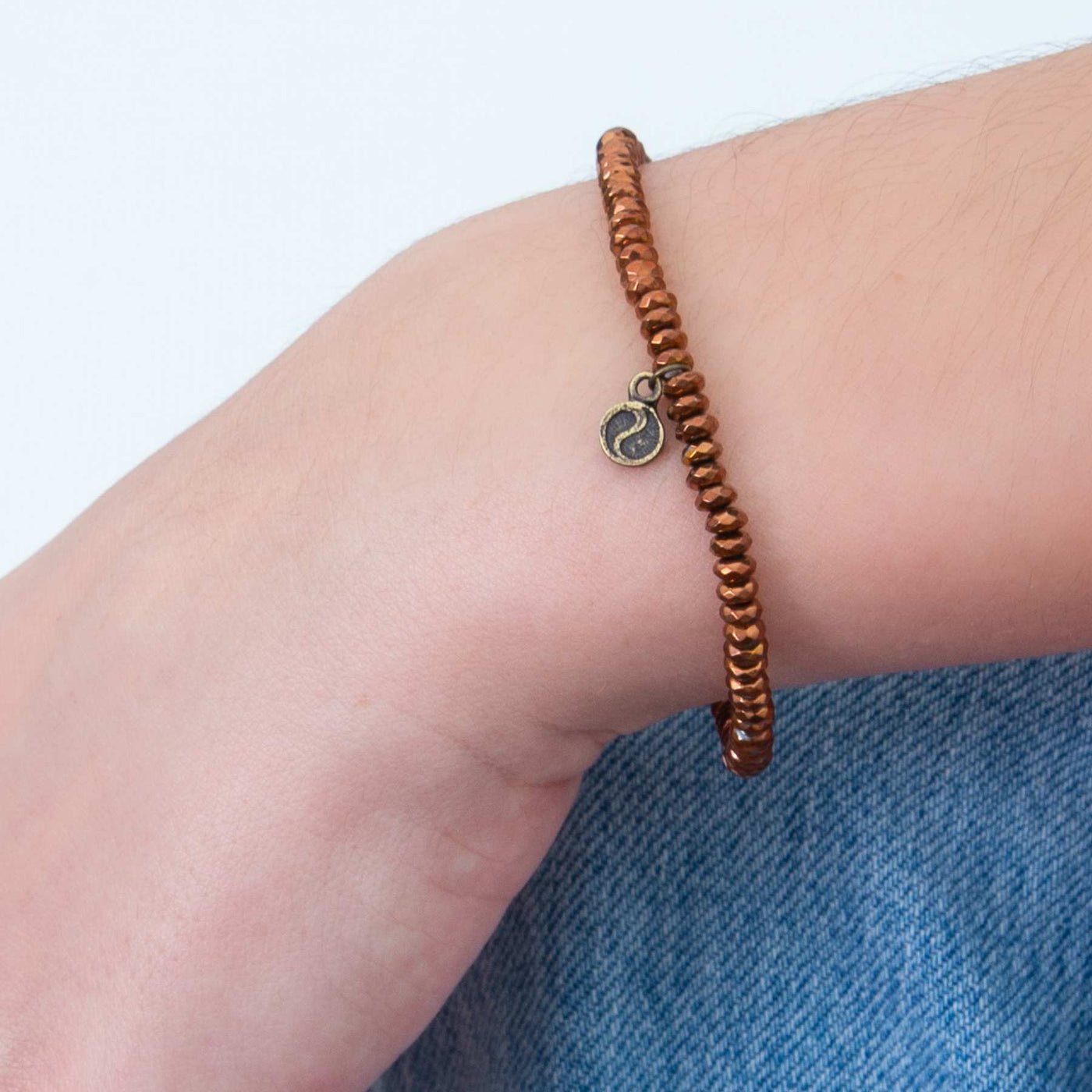Woman wearing a Copper-plated Hematite mini faceted gemstone dainty stretch bracelet by Energy Muse
