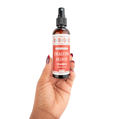 Woman with red nails holding plastic spray bottle of dragon's blood clearing room spray - Energy Muse
