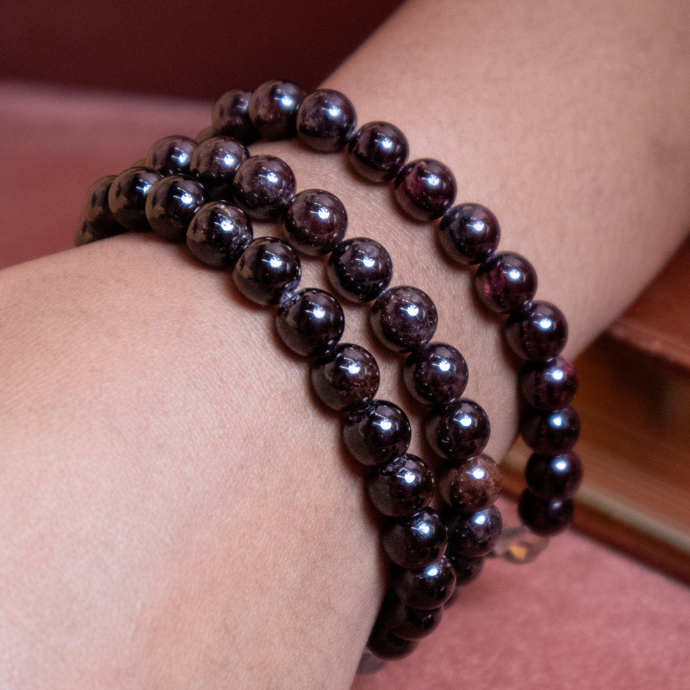Close up of woman's wrist with 3 Energy Muse garnet bead bracelets