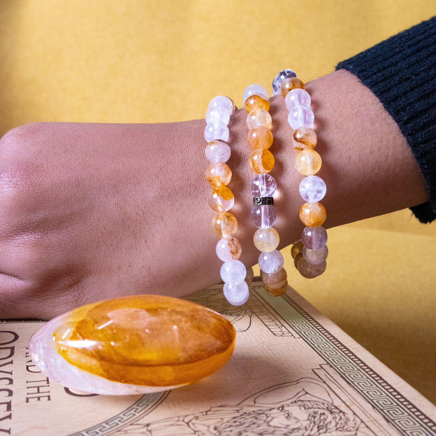 close up of genuine GOlden Healer Quartz touchstone and a woman wearing 3 GOlden Healer Quartz bracelets