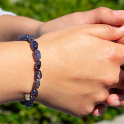 Woman wearing natural pebble shaped genuine indigo blue Iolite crystal bead elastic bracelet by Energy Muse