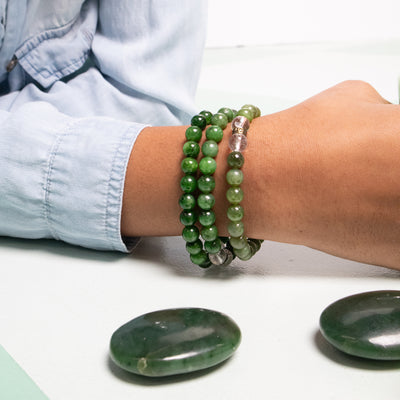 Close up of woman's wrist wearing 3 jade bracelets and 2 jade touchstones by Energy Muse