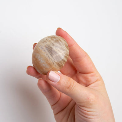 woman holding polished Peach Moonstone touchstone by Energy Muse