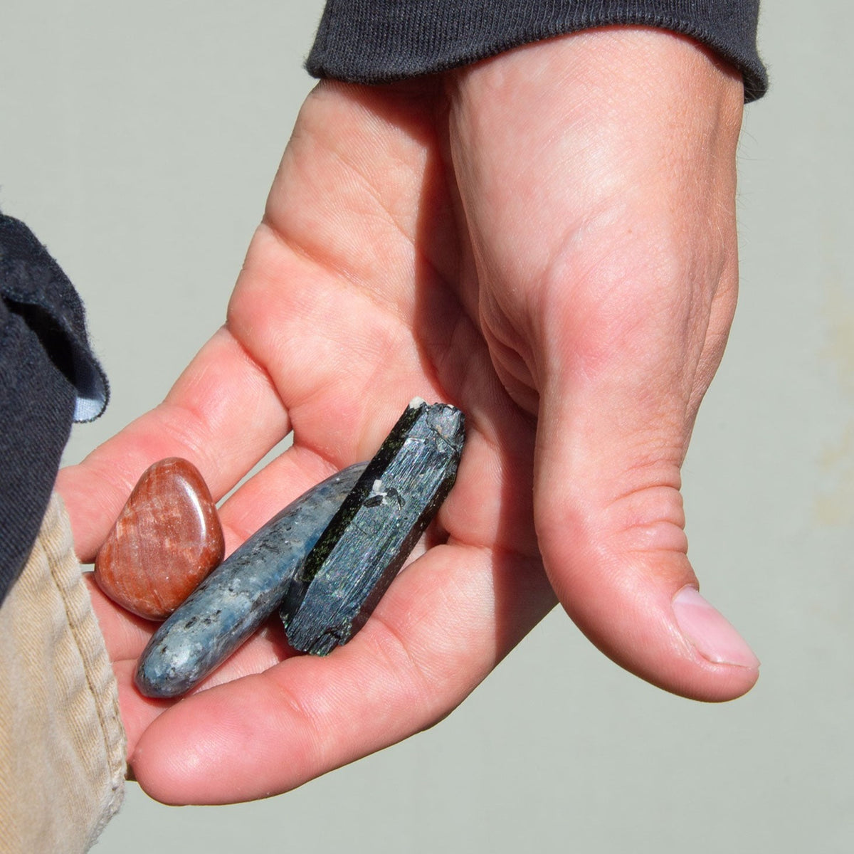 Man putting genuine Aegirine Blade, Blue Kyanite Mini Wand and Aragonite Tumbled Stone in pants pocket by Energy Muse.