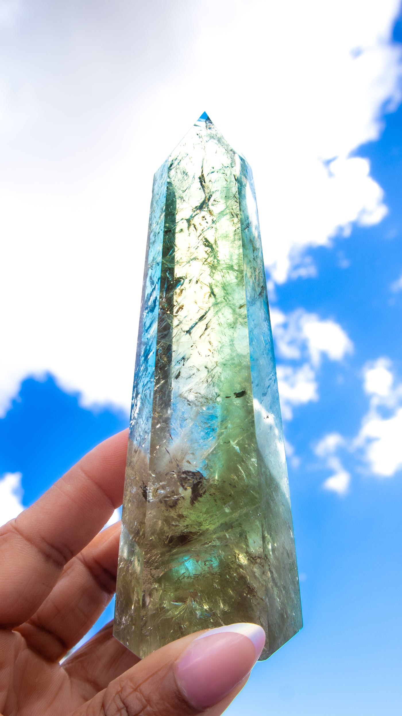 Woman holding Prasiolite point up to the sky to show detail and translucence by Energy Muse