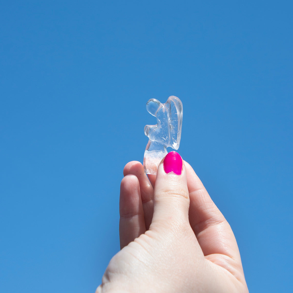 Woman holding up genuine Clear Quartz crystal carved into shape of kneeling praying winged angel by Energy Muse