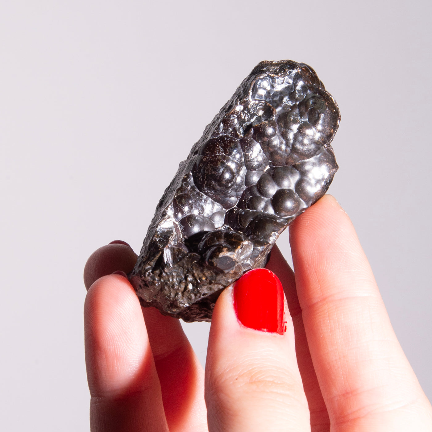 woman holding up raw hematite crystal cluster by Energy Muse