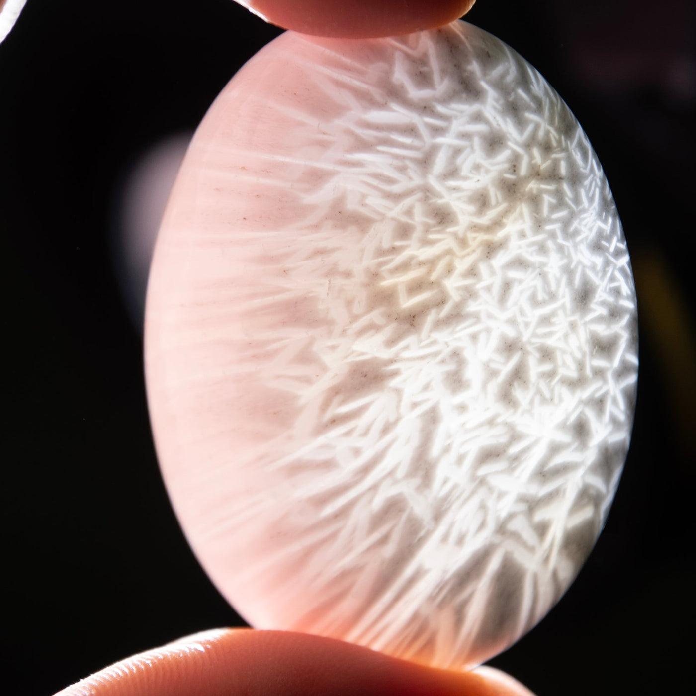 A genuine Scolecite crystal touchstone by Energy Muse with bright light shining through it displaying the unique inner pattern. 