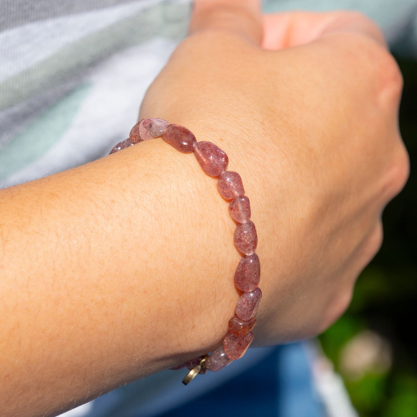 Woman wearing natural pebble shaped genuine Strawberry Quartz crystal bead elastic bracelet by Energy Muse