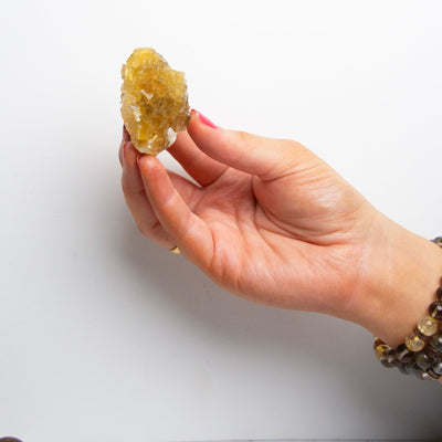 woman holding small yellow fluorite crystal cluster in hand to show size by Energy Muse