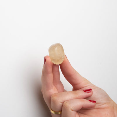 Woman holding honey-yellow lemon topaz polished stone by Energy Muse to show its size.