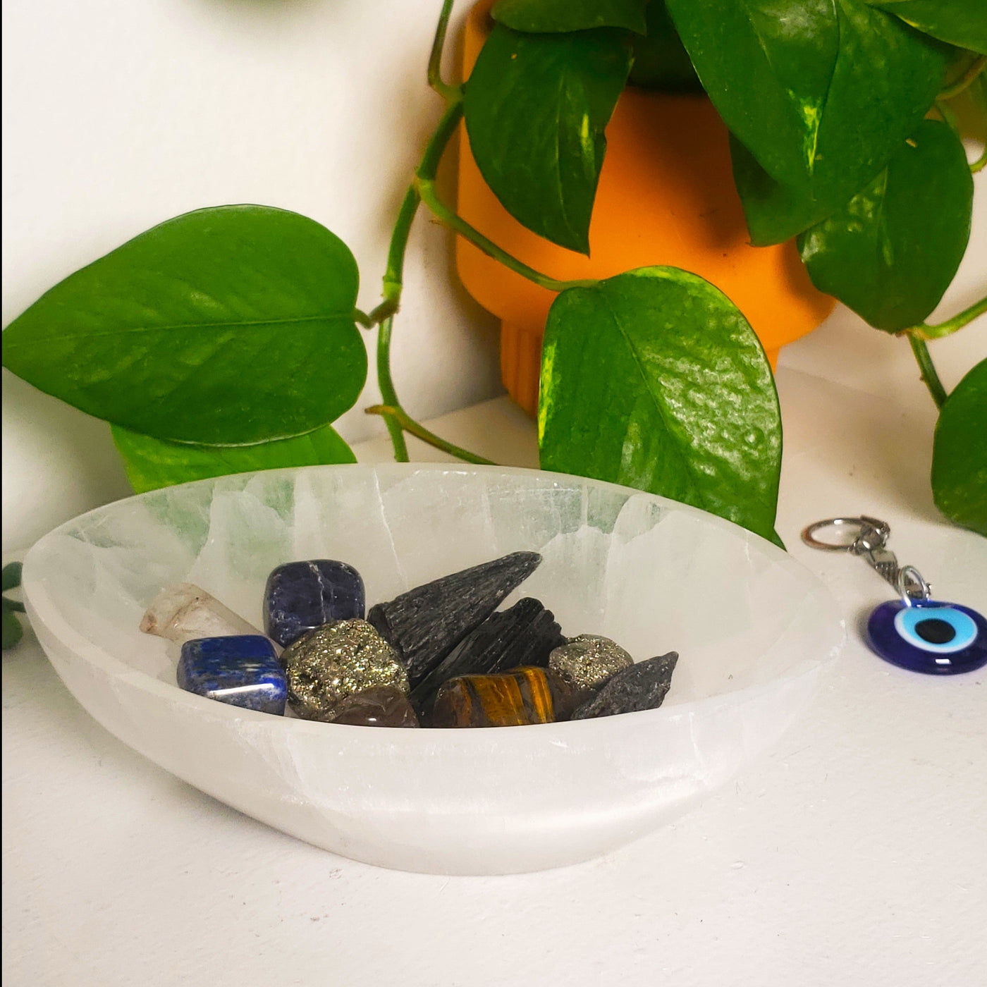at-home view of oval evil eye shaped Selenite charging bowl with tumbled crystals by Energy Muse