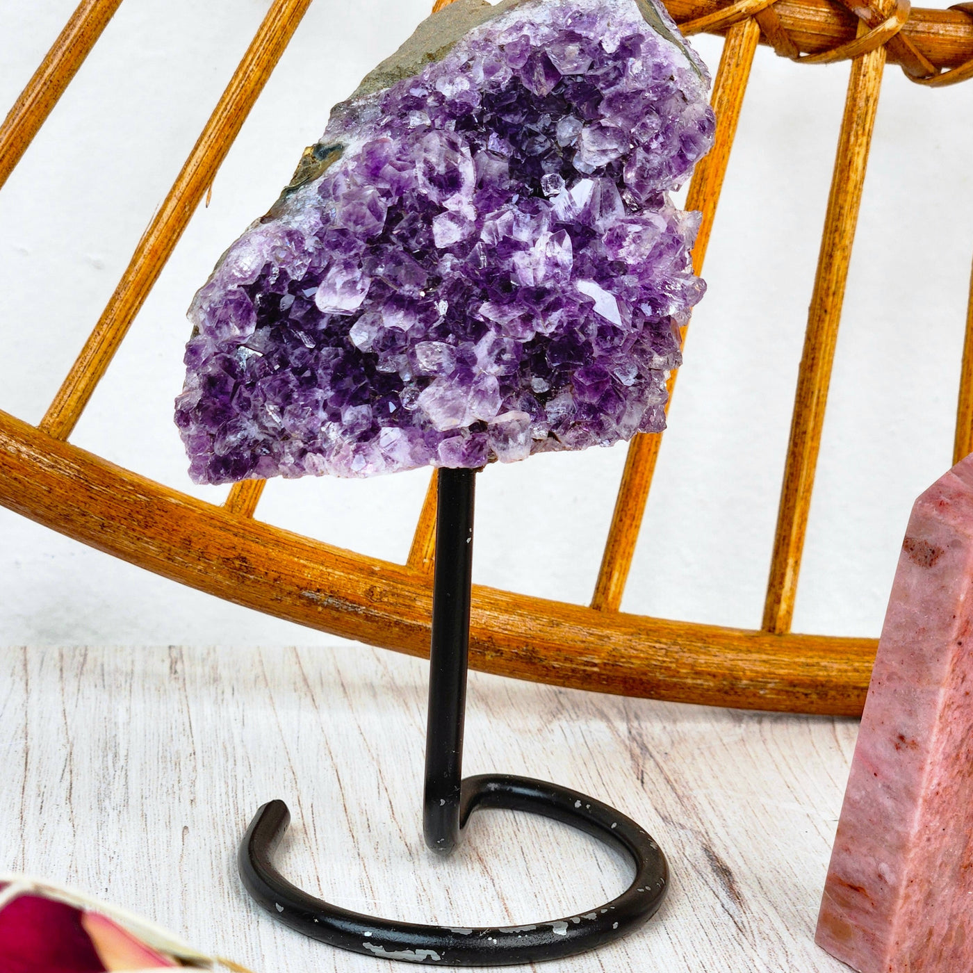 in-home view of genuine Amethyst cluster on simple black metal stand with rhodonite point by Energy Muse