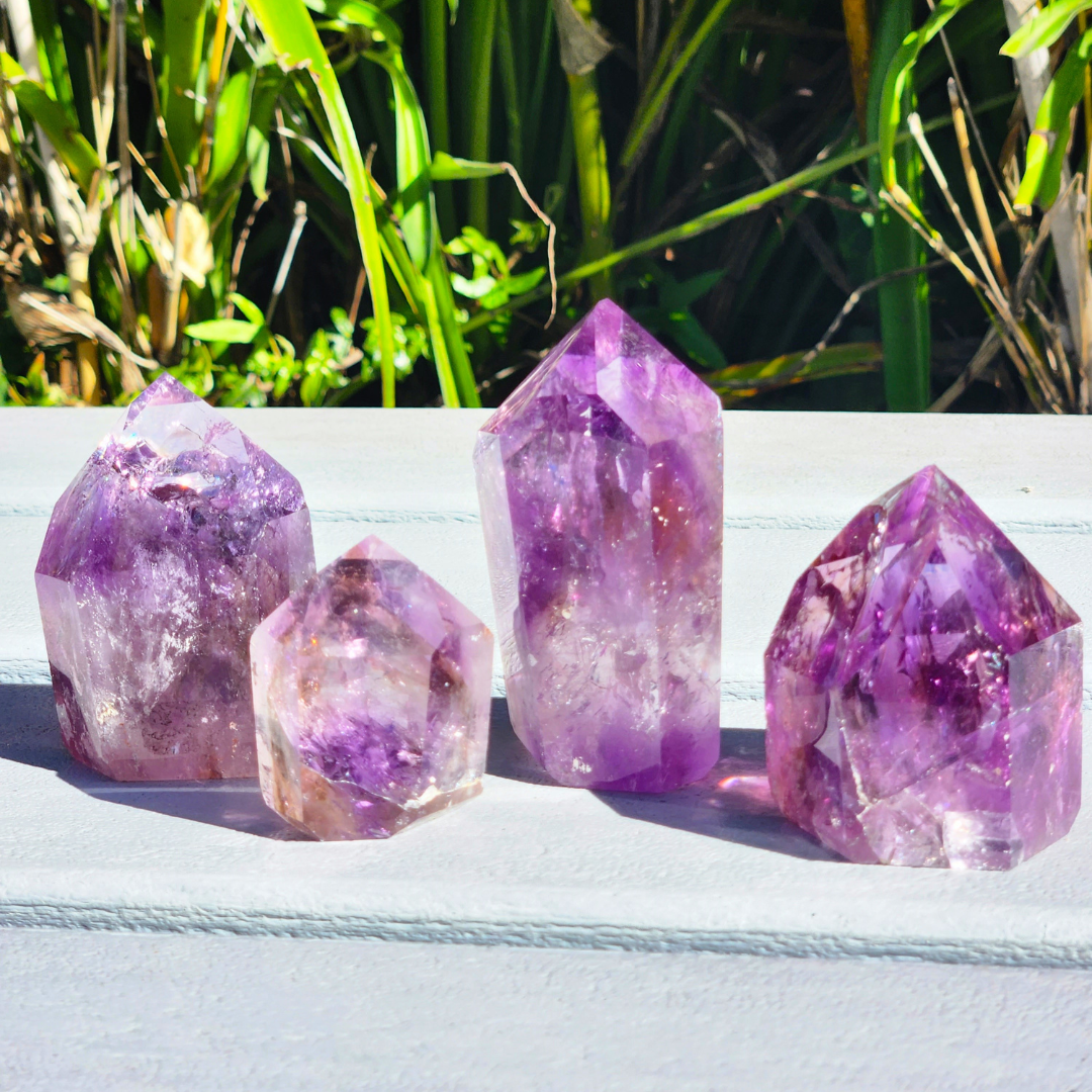 group of 4 Tucson Find Ametrine Freeform Point taken outside in natural light, highlighting the variety of the unique natural shapes of each by Energy Muse
