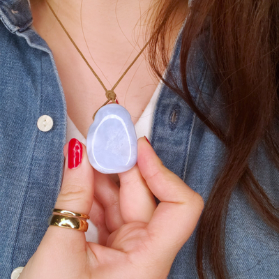 woman wearing Blue Lace Agate necklace and holding the pendant to show its relative size by Energy Muse