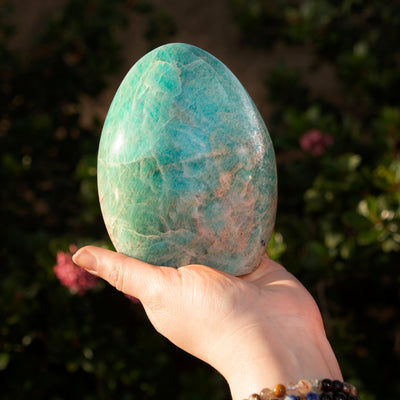 Woman holding Amazonite Freeform in one hand outdoors in nature to show its size by Energy Muse