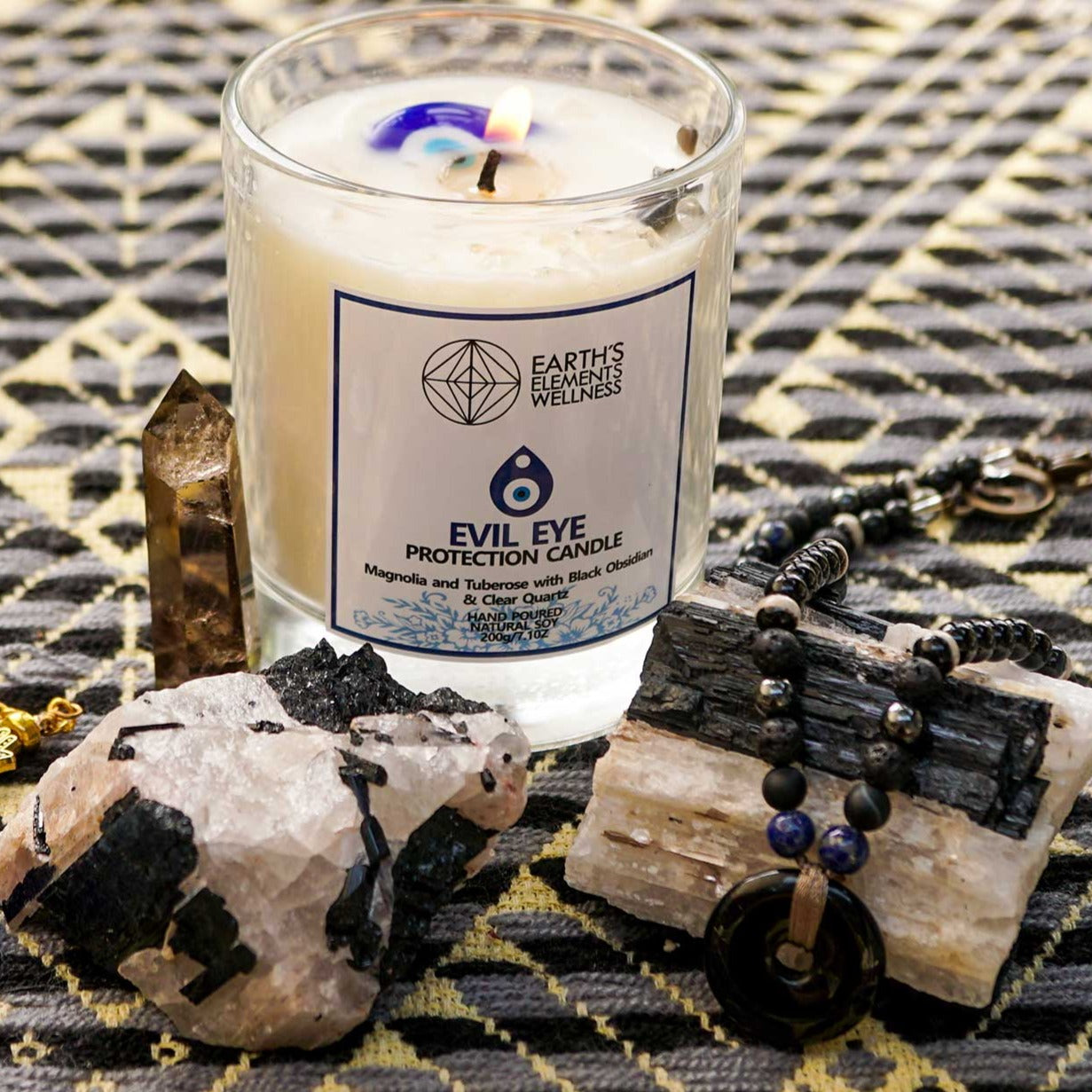 genuine raw clusters of Black Tourmaline crystal in Feldspar with an Evil Eye candle and blue evil eye nazar pendant by Energy Muse