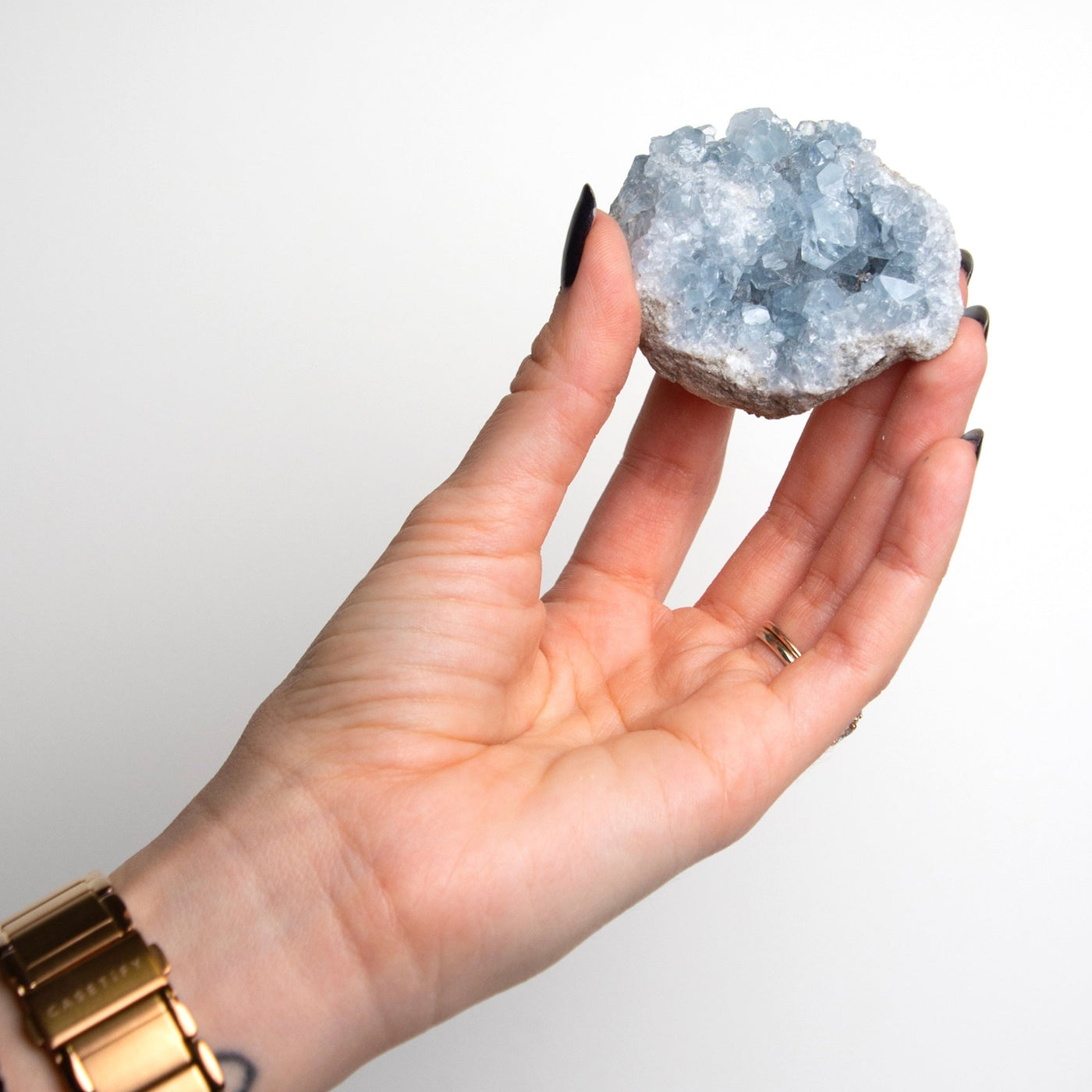 woman holding up semi raw celestite cluster geode crystal by Energy Muse