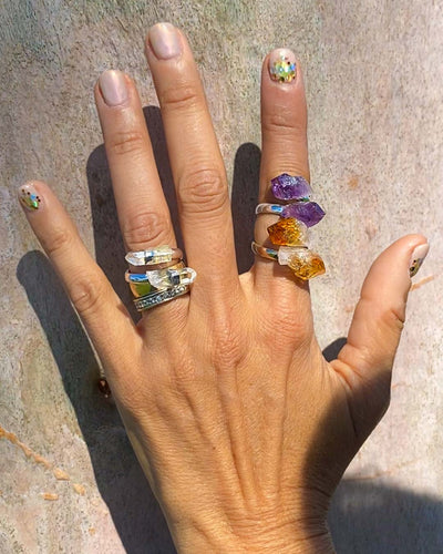 woman's left hand wearing amethyst crystal ring, citrine crystal ring and clear quartz ring 