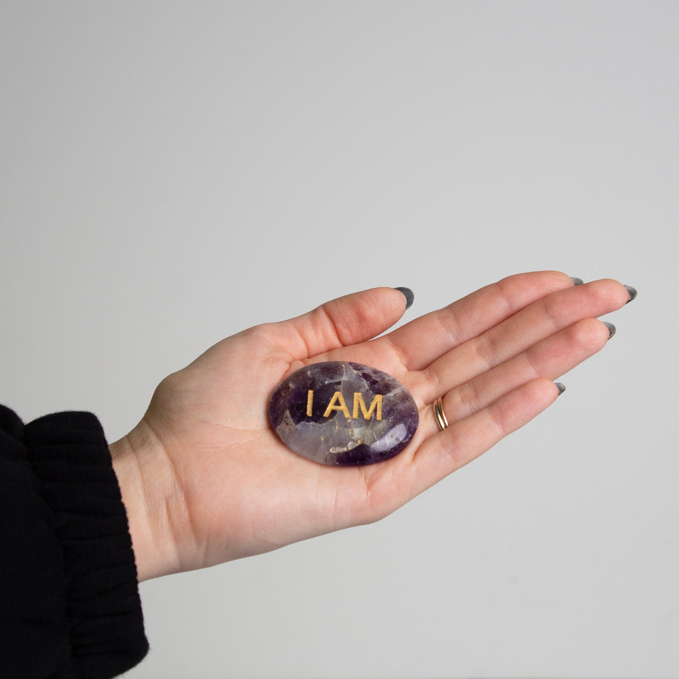 Woman holding Amethyst I AM Worry Stone in palm of her hand by Energy Muse