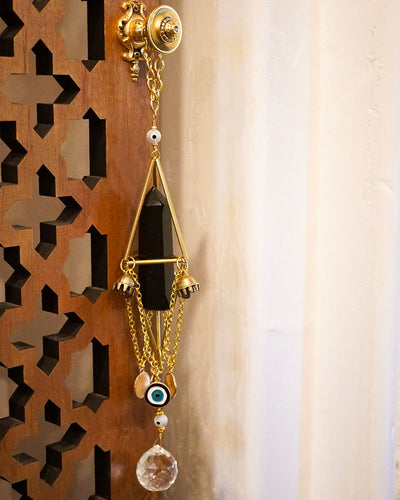 close up of gold crystal chandelier with natural black obsidian point, bell charms, evil eye charms, clear crystal faceted prism ball hanging on gold doorknob by Energy Muse