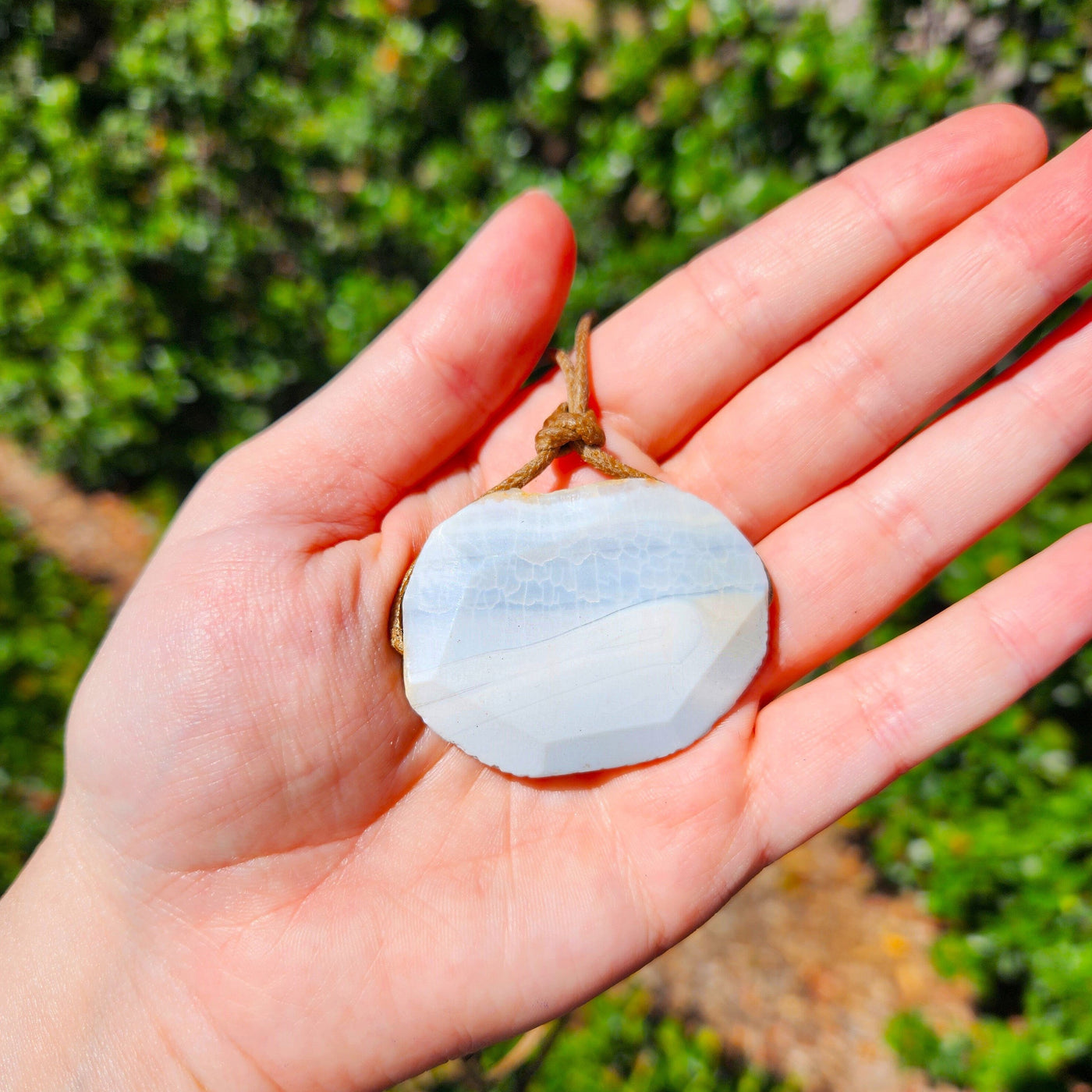 close up view of woman holding white agate pendant adjustable necklace by energy muse