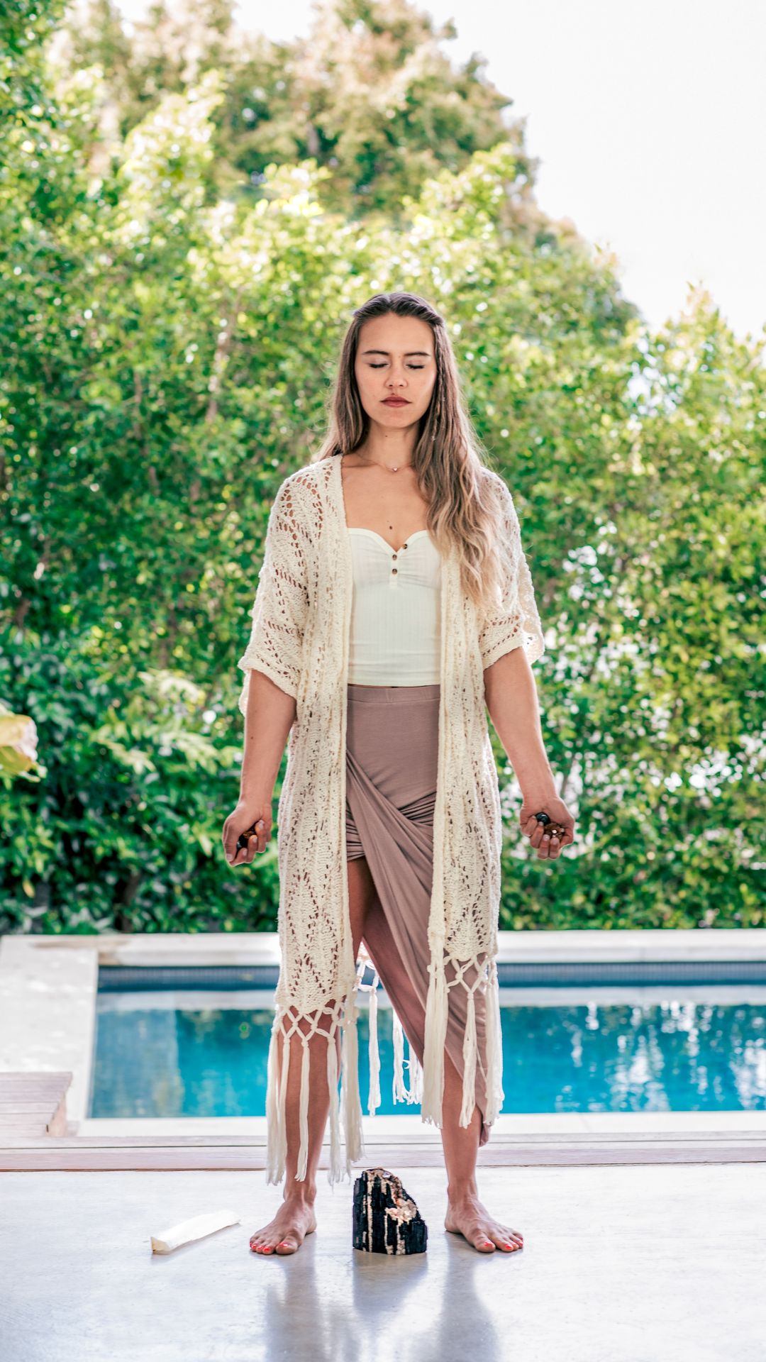 A woman standing by a pool with her eyes closed